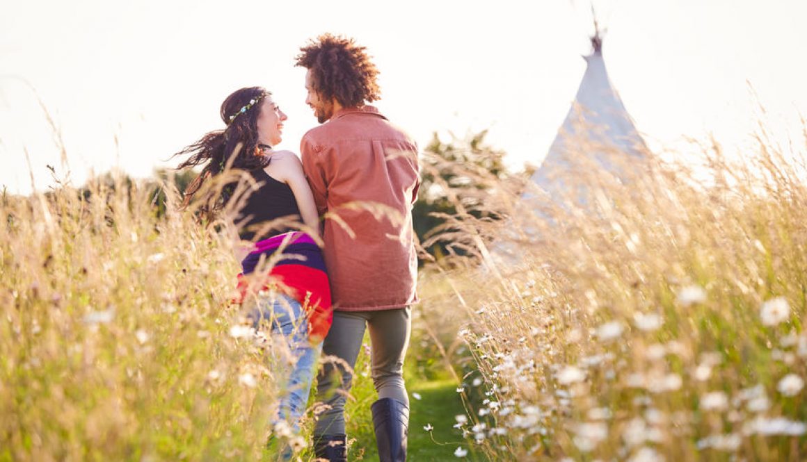 A romantic couple walk towards a tipi