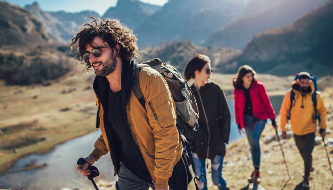 People walking along a mountain trail with water in the background.