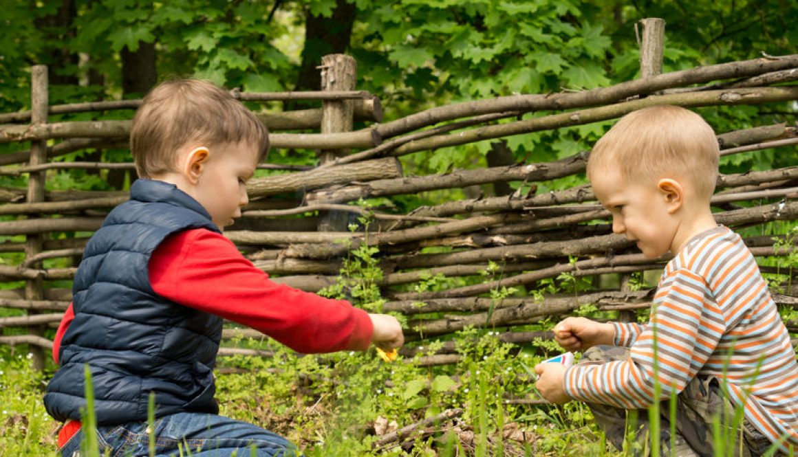 Young boy holding a burning match as he and a young friend play together at a rural campsite