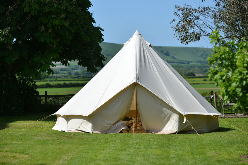 A bell tent in a field with a blue sky